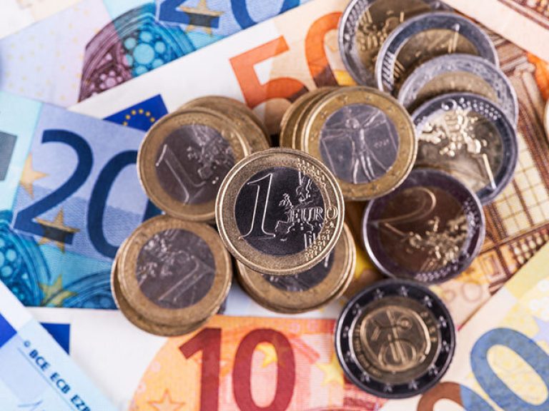 Coins in denominations of 1 and 2 euros against the background of euro banknotes of various denominations